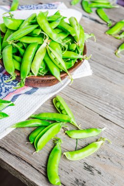 Genç yeşil bezelye pod, toprak çanak, rustik arka plan