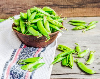 Genç yeşil bezelye pod, toprak çanak, rustik arka plan