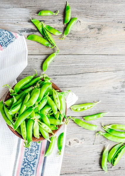 Young green peas in the pod, earthenware dish, rustic, top view — Stock Photo, Image