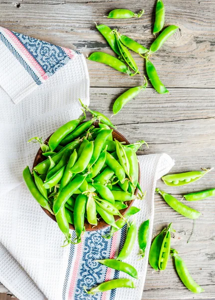 Guisantes verdes jóvenes en la vaina, plato de barro, rústico, vista superior — Foto de Stock