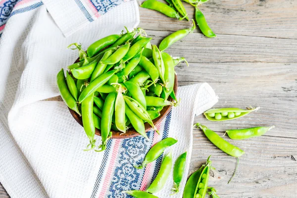 Guisantes verdes jóvenes en la vaina, plato de barro, rústico, vista superior — Foto de Stock