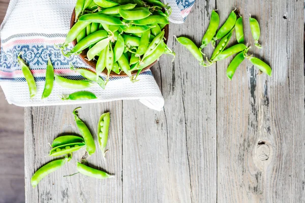 Young green peas in the pod, earthenware dish, rustic, top view — Stock Photo, Image