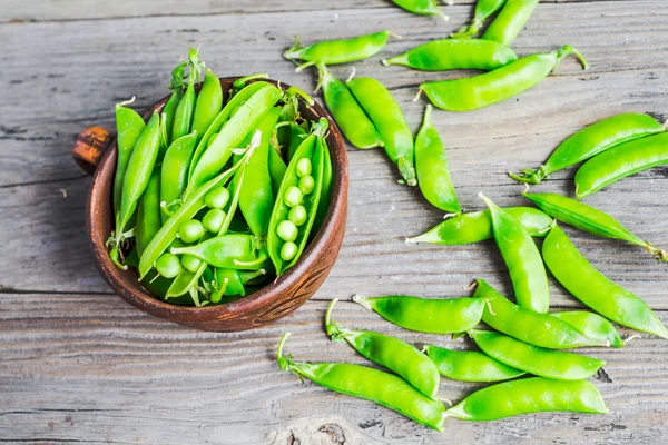 Gröna ärtor i skida ung på grå trä bakgrund, rustik, — Stockfoto