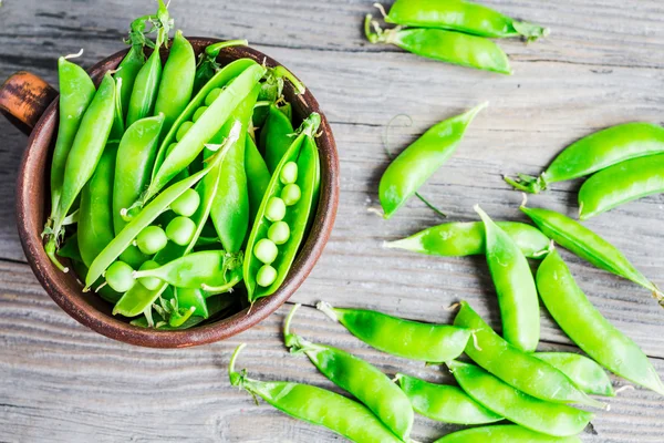 Green peas in pods young on gray wooden background, rustic, — Stock Photo, Image