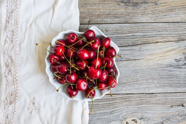 yeşil bahçe bir arka plan üzerinde bir tabak içinde taze kırmızı kiraz, 