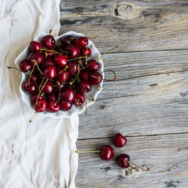 yeşil bahçe bir arka plan üzerinde bir tabak içinde taze kırmızı kiraz, 