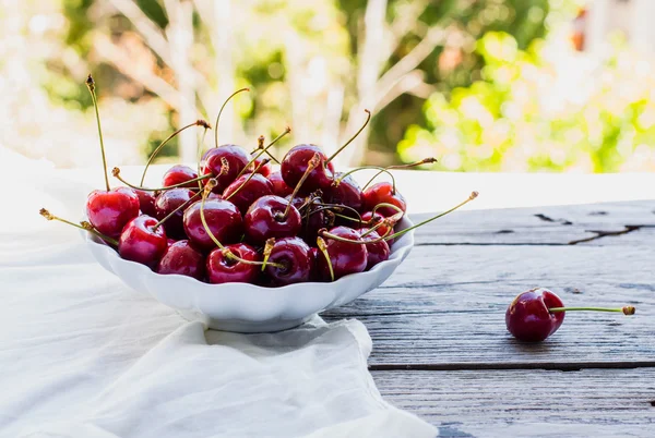 Frische rote Kirschen in einem Teller, auf einem Hintergrund von grünem Garten, — Stockfoto