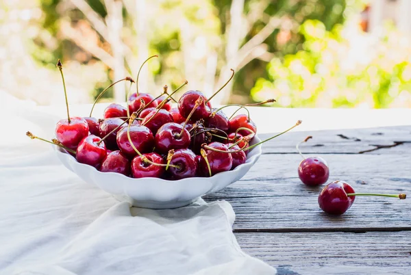 Frische rote Kirschen in einem Teller, auf einem Hintergrund von grünem Garten, — Stockfoto