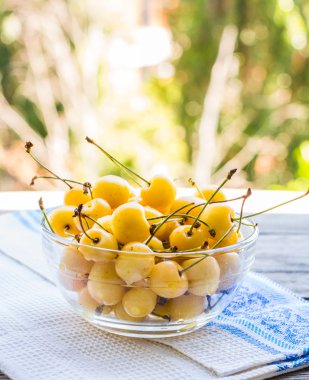 Yeşil garde bir arka plan üzerinde bir tabak içinde taze sarı kiraz