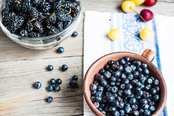 Fresh blueberries, cherries and mulberries on a gray wooden back — Stock Photo, Image