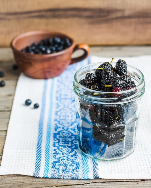 Frische schwarze Maulbeeren im Glas auf dem grauen Holzbackgro — Stockfoto