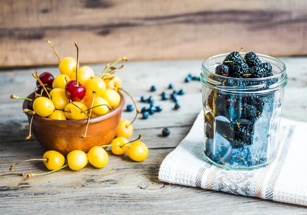 Frische rohe Blaubeeren, gelbe Kirschen und Maulbeeren auf grauem Holz — Stockfoto