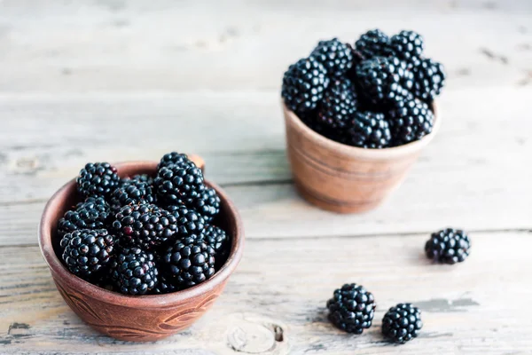 stock image Fresh sweet blackberry in clay pots on a wooden table, closeup