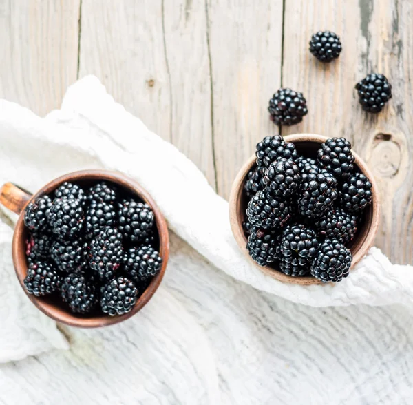 Fresh blackberry in clay pots on a wooden table,top view — Stock Photo, Image