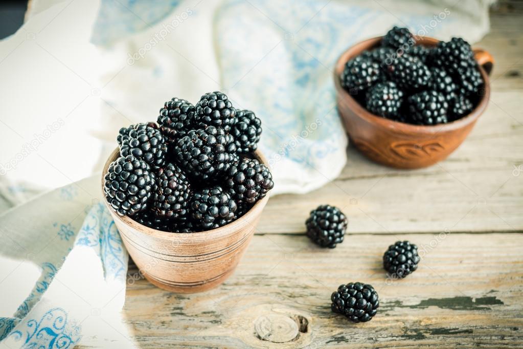 Fresh sweet blackberry in glass on a wooden table, closeup