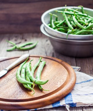 ham yeşil fasulye bir ahşap tahta ve bir kevgir içinde bıçak