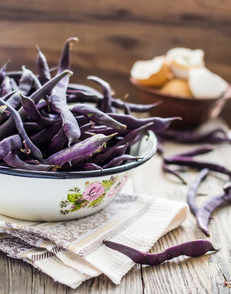 fresh purple string beans on a gray wooden table
