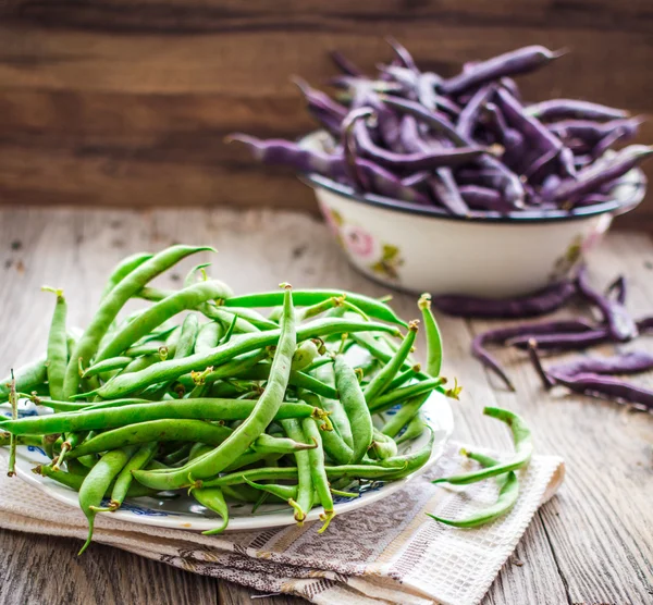 Raw purple and green beans on a gray wooden table, clean eating — Stock Photo, Image