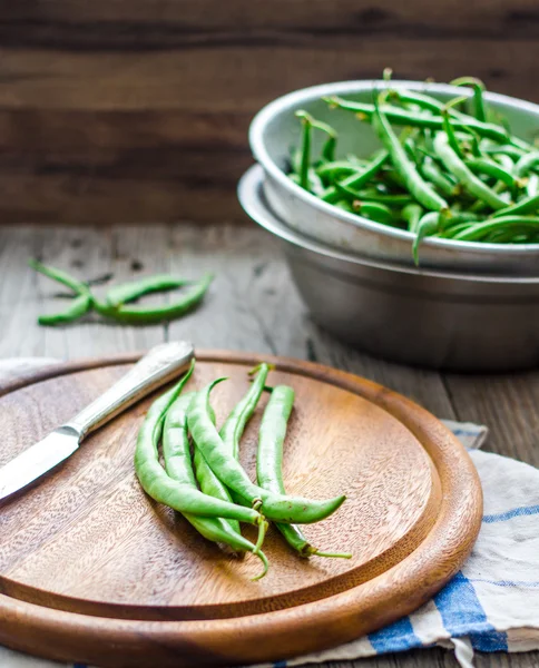 Raw green beans on a wooden board and in a colander,knife — Stock Photo, Image