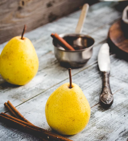 Желтая груша на деревянной доске, коричные палочки, здоровая закуска — стоковое фото