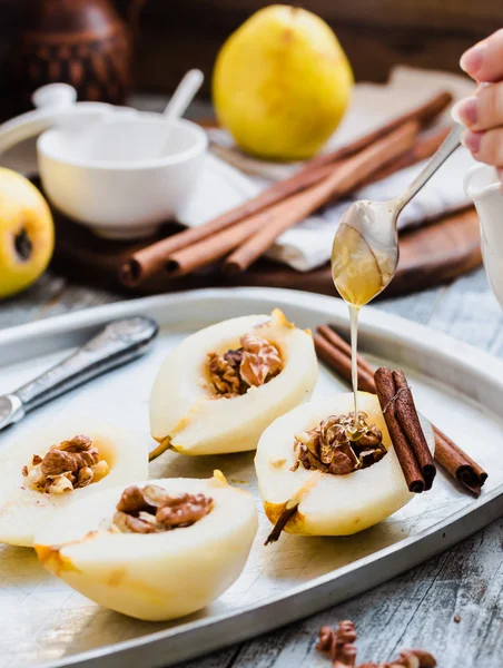 クルミ、シナモン棒、調理プロセスで梨に蜂蜜を追加します。 — ストック写真