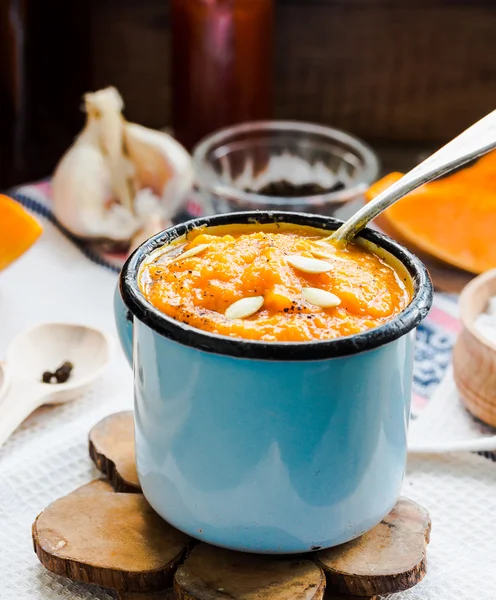 Autumn pumpkin soup in a blue mug, rustic background — Stock Photo, Image