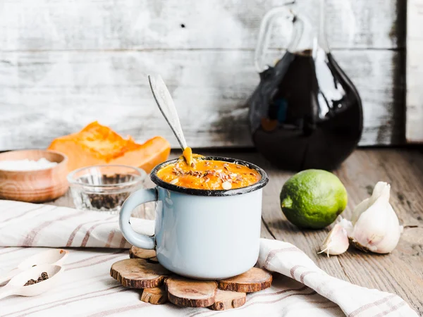 Autumn pumpkin soup in a blue mug, rustic background — Stock Photo, Image