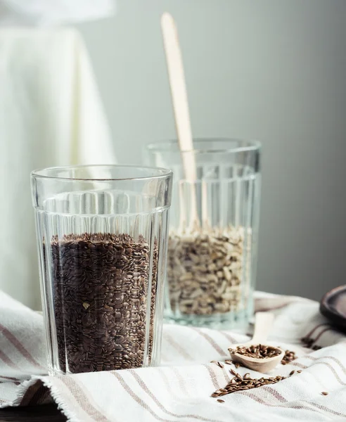 Семена льна и подсолнечника в стакане с деревянной ложкой — стоковое фото