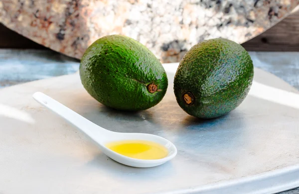 Масло авокадо в ложке и свежий зеленый авокадо — стоковое фото