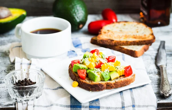 Toast with fresh avocado, tomato and corn, a cup of coffee, brea — Stock Photo, Image