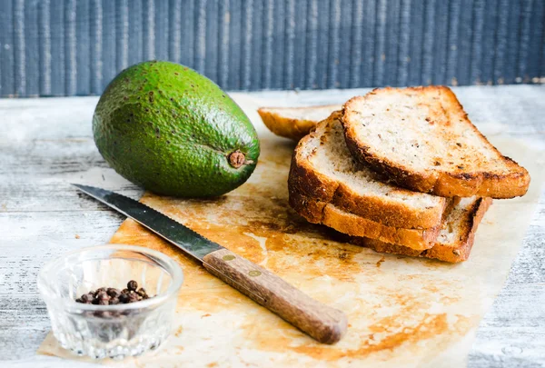 Bread and a whole avocado with pepper and garlic — Stock Photo, Image