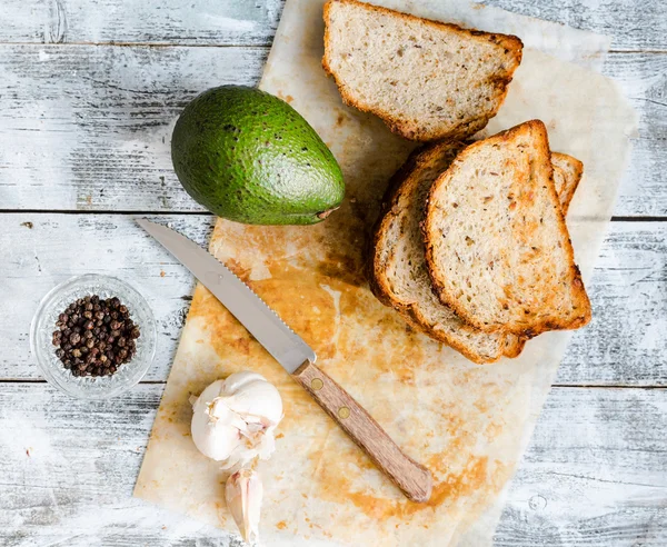 Bread and a whole avocado with pepper and garlic — Stock Photo, Image