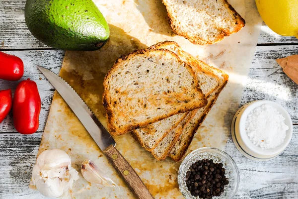 Bröd och en hel avokado med körsbärstomater, peppar och garli — Stockfoto