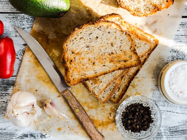 Bröd och en hel avokado med körsbärstomater, peppar och garli — Stockfoto