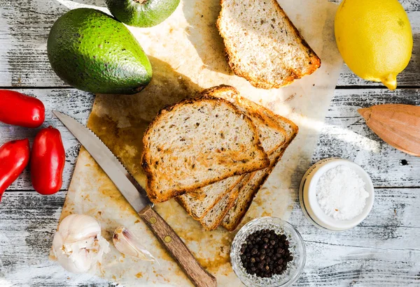 Pane e un avocado intero con pomodorini, pepe e garli — Foto Stock