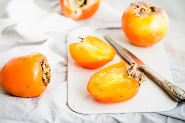 Fresh juicy persimmons on a light background, raw fruit — Stock Photo, Image