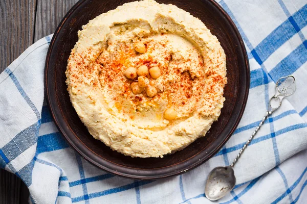 A bowl of creamy hummus with olive oil, paprika and pita chips — Stock Photo, Image