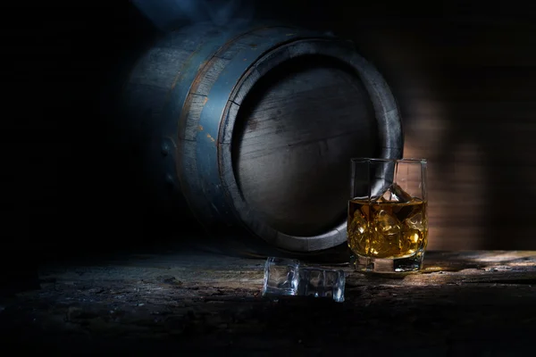 Keg and a glass of whiskey with ice on a wooden table — Stock Photo, Image