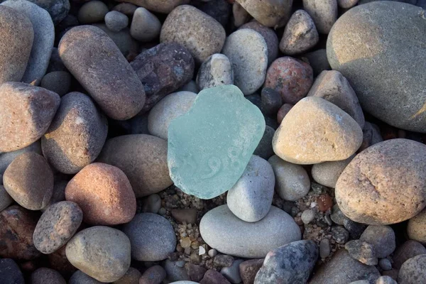 Part of a piece of glass with numbers 8,6 and 4 on natural stone background