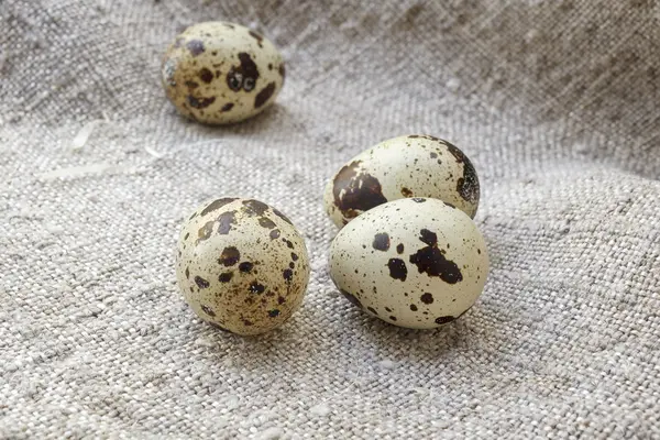Three quail eggs. The table covered with a rough cloth. — Stock Photo, Image