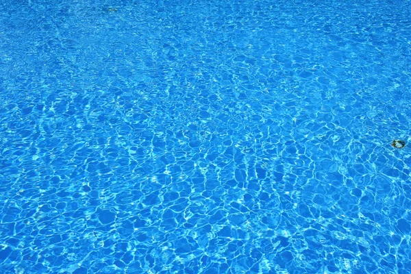 Rippled blue water surface. Water level in the pool. Light reflections on the surface of the water full of ripples.