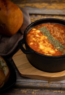 Yanında sarımsaklı ekmek olan domates çorbası.