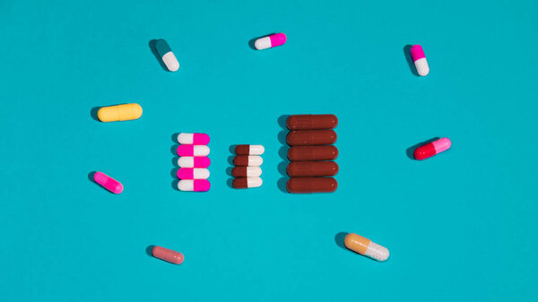 Rows of pills with different pills around on blue background. Medical concept. Flat lay, Copy space