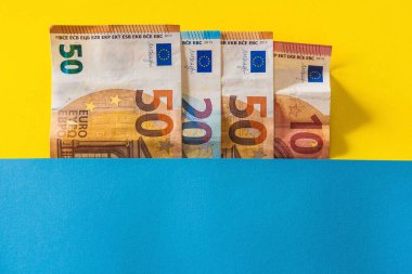 Sarı ve mavi arkaplan arasında 50, 20 ve 10 avroluk düz banknotlar.