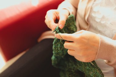 Evdeki kanepede iplik yumağı ören bir kadının en iyi resmi. El yapımı konsept.