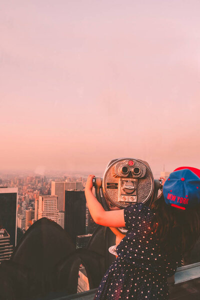 Manhattan, NYC, United States of America- July, 18, 2013. Girl looking at the Manhattan skyline from an overlook during sunset.