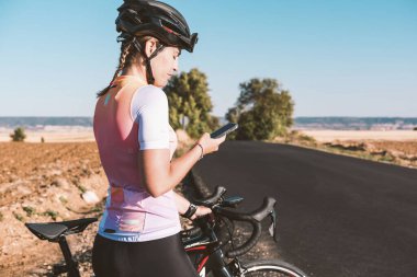 Genç bisikletçi kadın cep telefonuyla konuşuyor. Bisiklet konsepti. Spor konsepti.