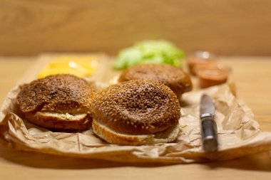 Masada hamburger ekmeği, marul ve peynir var. Ev yapımı hamburgerler..