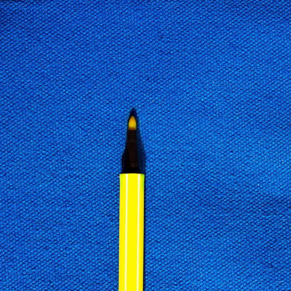 Stylo de couleur jaune sur fond de toile bleue — Photo