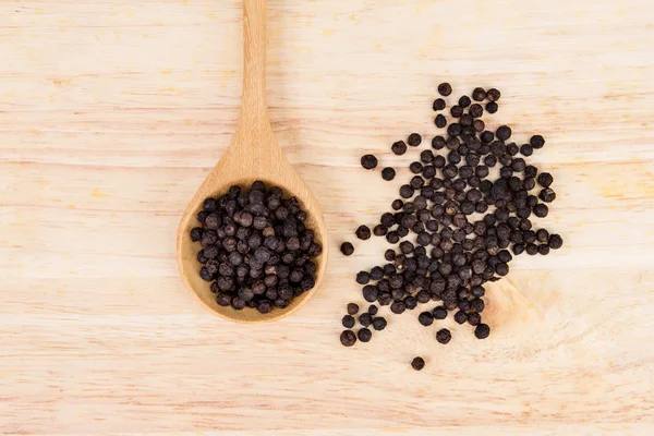 Primer plano seco pimienta negra en plato de madera —  Fotos de Stock